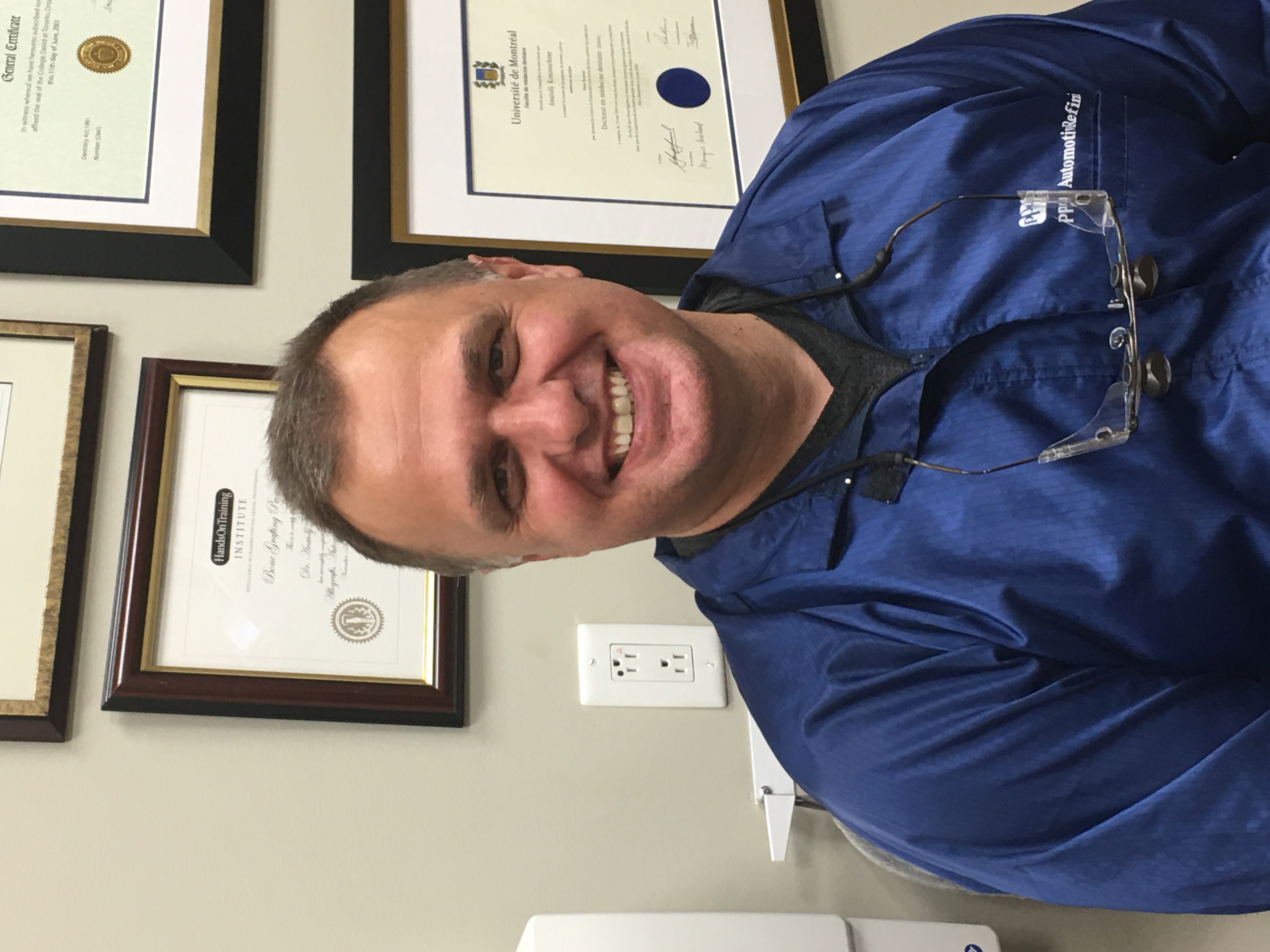 Dr. Anatolij Koniouchine smiling in front of his credentials and diplomas