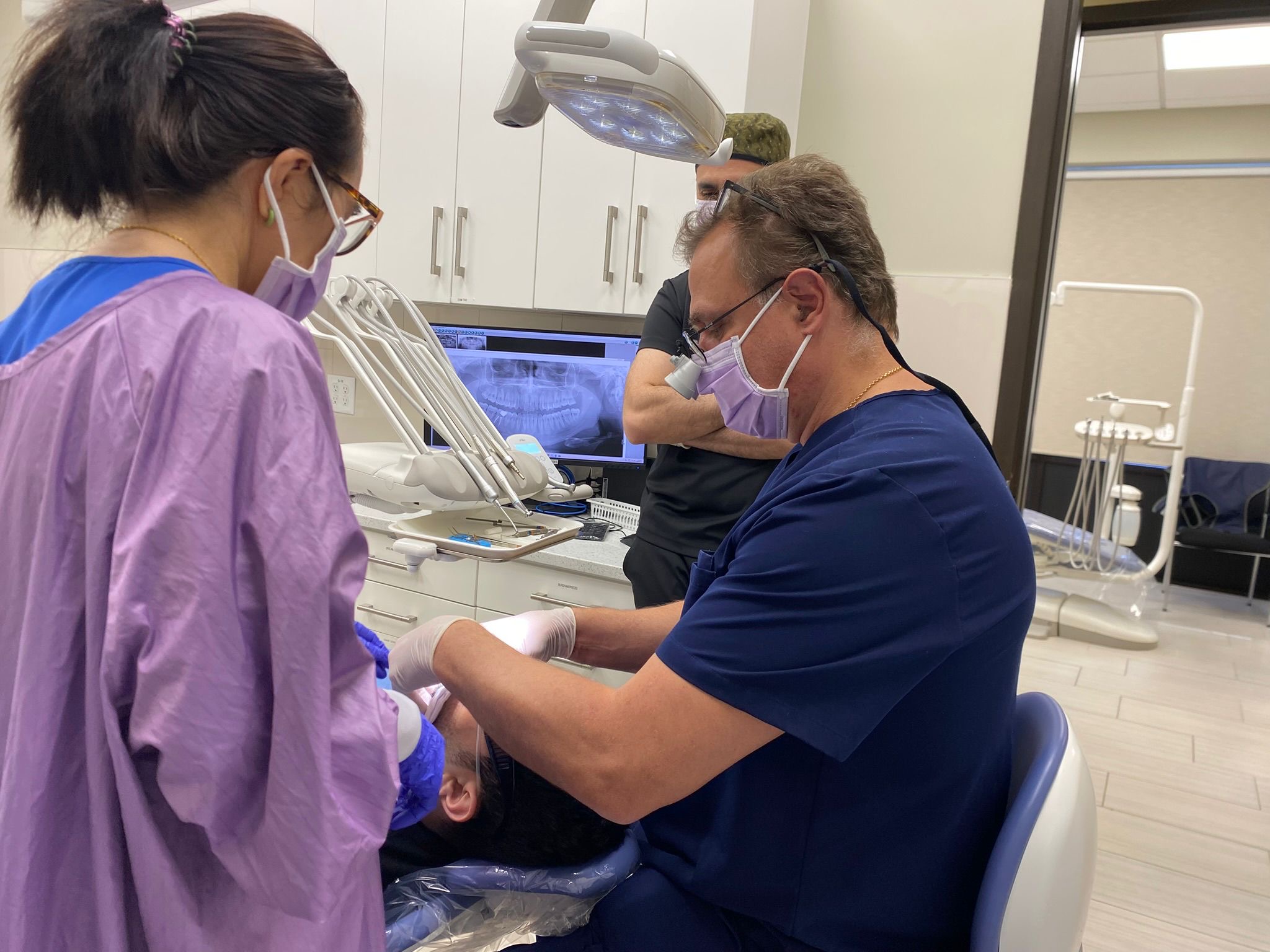 Dr. Koniouchine working with surgical loupes and panoramic X-ray on screen
