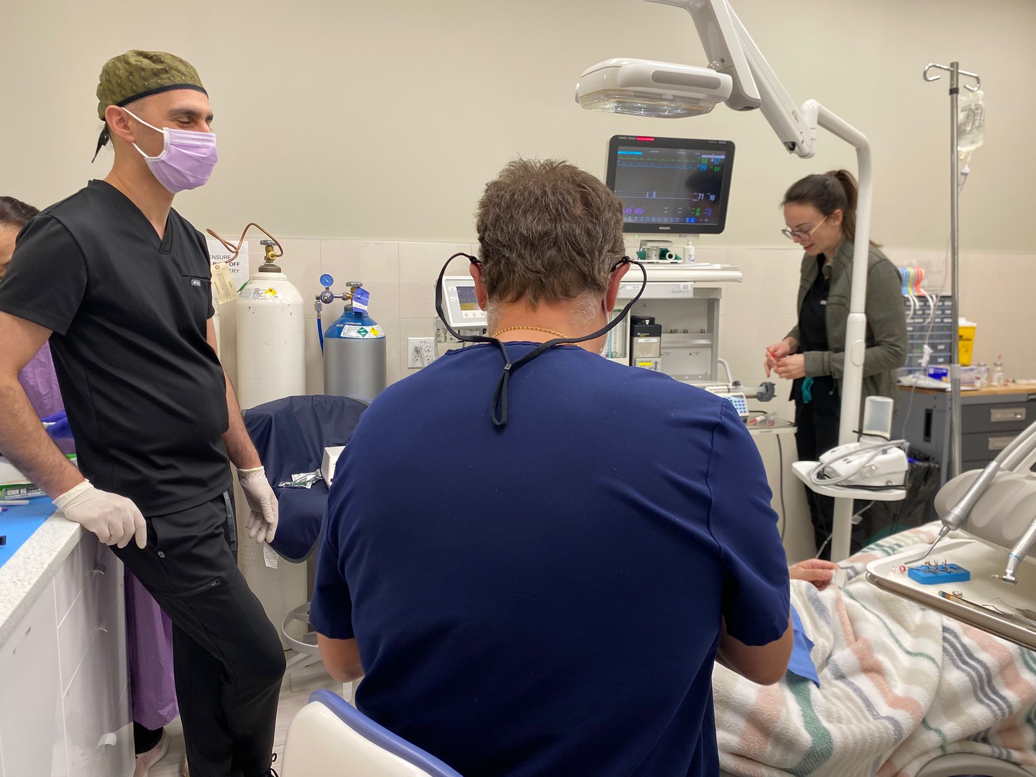 Anesthesiologist monitoring vital signs with Philips display, gas cylinders, and full medical equipment